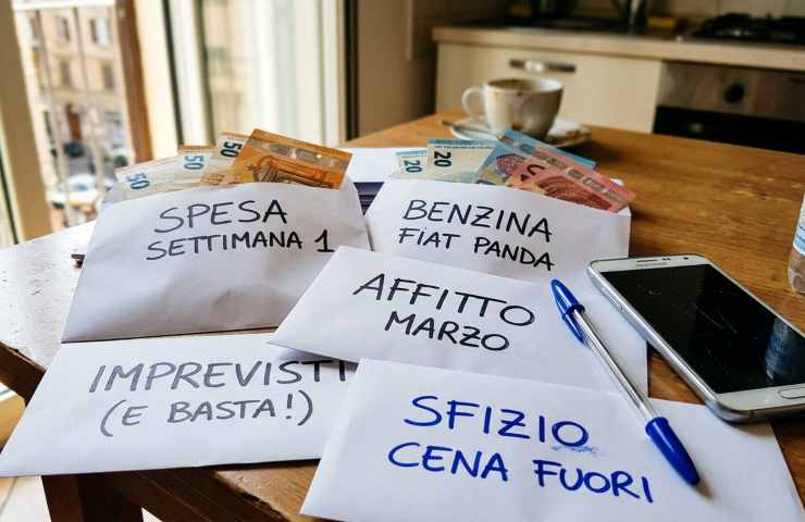 Risparmio contanti metodo buste cash stuffing 2026: buste scritte a mano con banconote euro per gestione budget familiare su tavolo in cucina.