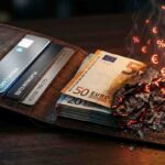 Un portafoglio in pelle aperta mostra carte di credito moderne e integre accanto a banconote da Euro bruciate, dalle quali si alzano simboli di tasse (%) e matematici luminosi, rappresentando il rischio fiscale e la transizione al digitale dei Bonus 2026.