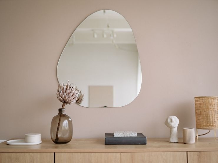 parete con specchio ovale e mobile con vaso e suppellettili